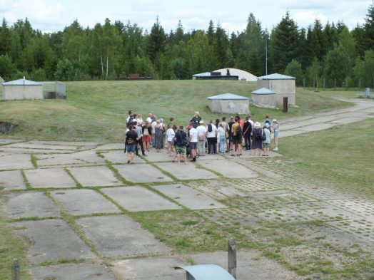 Grupė žmonių klausosi gido ekskursijos šaltojo karo ekspozicijoje
