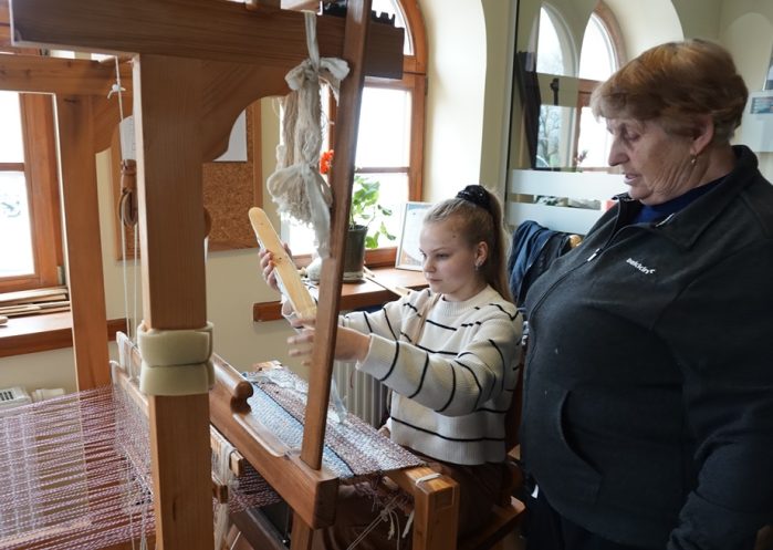 Mergaitė su staklėmis audžia audinį